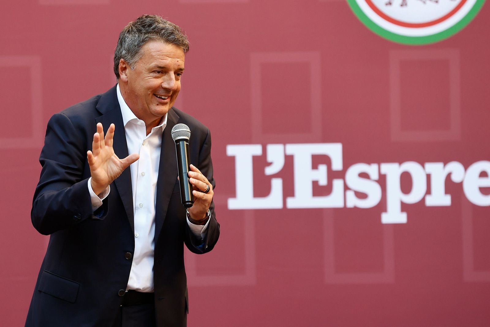 Matteo Renzi sul palco davanti al backdrop dell'evento